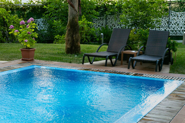 Tranquil backyard scene featuring a sparkling blue swimming pool surrounded by lush greenery, comfortable lounge chairs, and vibrant flowers, creating a serene atmosphere for relaxation and leisure