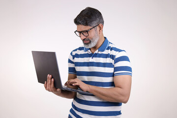 Portrait of a Indian handsome middle aged man working on laptop on white studio background