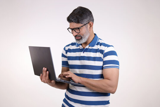 Portrait of a Indian handsome middle aged man working on laptop on white studio background