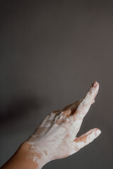 Close up of female hand covered with clay, looking like a sculpture, on neutral background with copy space for text. Concept of art, creativity, pottery and mindfulness.