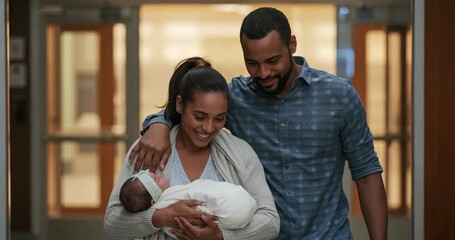 Stepping through doors, parents carrying newborn walking down hospital corridor expressing relief - Powered by Adobe