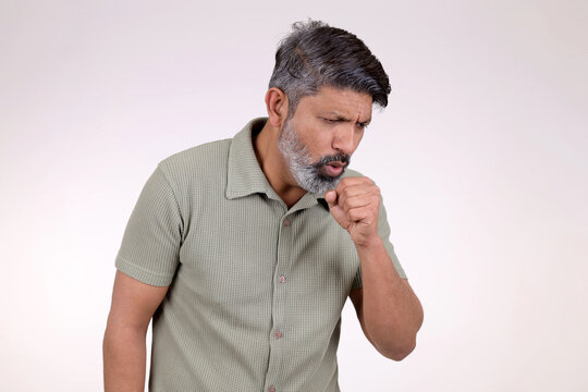 Deep coughing indian middle aged man suffered from asthma. guy holding fist close to mouth and cough. Pain in chest