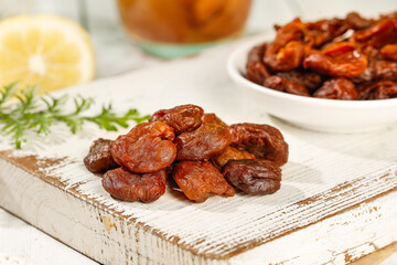 Fujian Gaozhou Cinnamon Flavored Dried Lychee Fruits with Meat Pieces on Rustic White Wood Board
