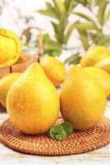 Fresh Yellow Lemons with Water Droplets on Wicker Mat with Tropical Pineapple Background