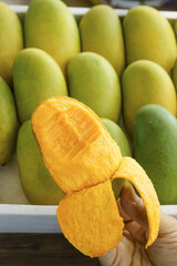 Fresh Green Mangoes at Market Display with Peeled Mango Showing Orange Flesh - Tropical Fruit Vendor
