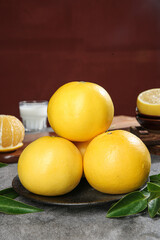 Fresh Fujian Pomelo Citrus Fruits on White Plate with Green Leaves and Milk Glass