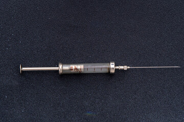 Reusable syringe 2 ml. Glass and metal. Old medical equipment for injection. Black background