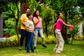 Fototapeta premium Indian family playing Tennikoit ring game outdoors, enjoying quality leisure time together
