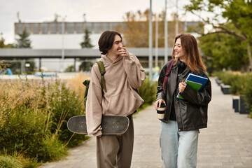 Loving couple enjoying a sunny walk together in the park with skateboard and books
