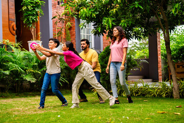 Fototapeta premium Indian family playing Tennikoit ring game outdoors, enjoying quality leisure time together