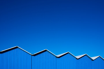 Wooden changing cabins against a clear blue sky. Minimalist beach scene in summertime. Color concept. Abstract architectural photography