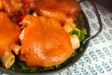 Golden Glazed Pork Trotters in Cast Iron Pan - Traditional Deli Cuisine with Secret Sauce