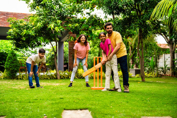 Indian Asian family bonding through outdoor cricket batting in garden, enjoying fun and play