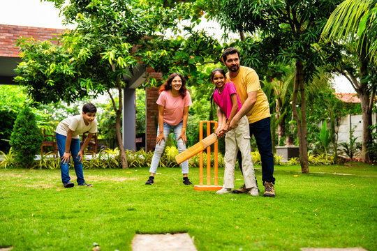 Indian Asian family bonding through outdoor cricket batting in garden, enjoying fun and play
