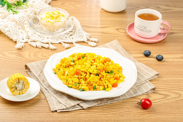 Golden scrambled eggs with corn kernels and vegetables healthy breakfast meal on wooden table