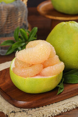 Fresh Pomelo Citrus Fruit Segments in Natural Green Rind on Wooden Board