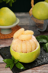 Fresh Pomelo Citrus Fruit Peeled and Segmented Ready to Eat with Tropical Leaves on Wooden Table