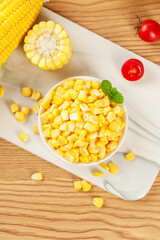 Fresh Golden Corn Kernels in Bowl with Tomatoes on Wooden Cutting Board