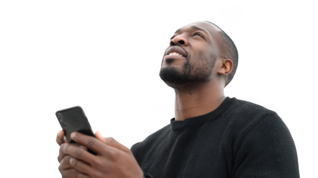 Man in black shirt holding a phone and looking up with a black background is in the image