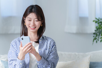 スマホを使う笑顔の若い女性