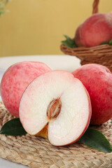 Fresh Red Peaches Cut Open Showing White Flesh and Pit on Natural Wicker Surface