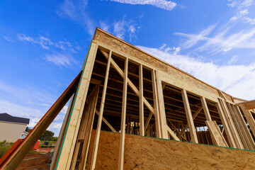 Fototapeta premium Workers are building house wooden frames beams in residential neighborhood, wooden structures, clear weather.