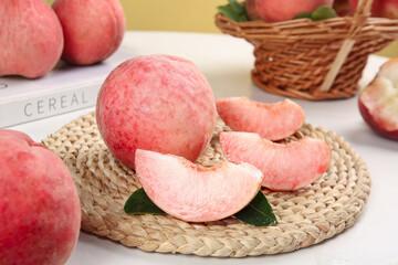 Fresh ripe peaches on wicker basket with sliced fruit pieces showing juicy pink flesh and natural organic harvest