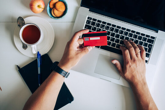 Man using laptop and holding credit card on desk with coffee cup and notebook. Concept of online shopping, ecommerce and digital payment.
