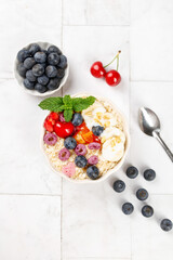 Healthy Oatmeal Bowl with Fresh Berries and Banana Breakfast on White Wood Background