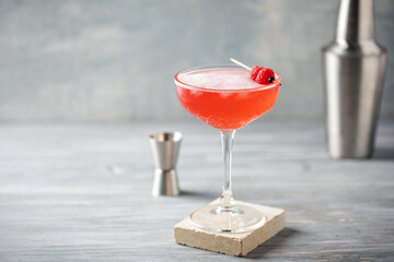 Alcoholic cocktail clover club with raspberries in a cocktail glass on the table.