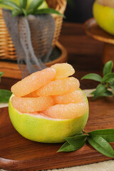 Fresh Pomelo Citrus Fruit Segments in Natural Kitchen Setting with Wooden Board and Green Leaves