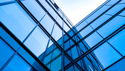 Modern glass office building with reflective windows against the sky.