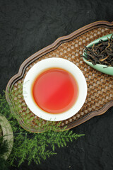 Organic Dahongpao Oolong Tea Ceremony in Traditional Garden Setting with Bamboo Tray and Dried Tea Leaves