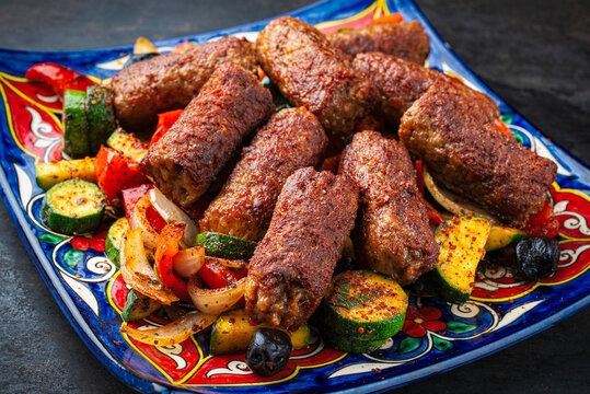 Traditional Croatian cevapi spicy meat ball rolls with troasted vegetables served  on plate
