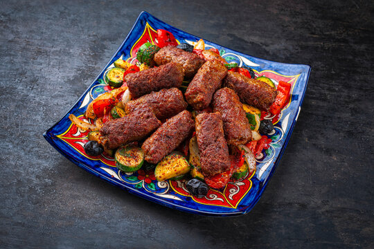 Traditional Croatian cevapi spicy meat ball rolls with troasted vegetables served  on plate