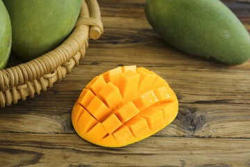 Fresh Juicy Mango Cubes with Green Mangoes in Basket on Wooden Table