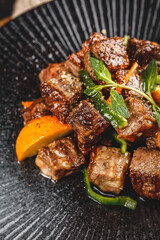 Grilled Diced Australian Beef Cubes with Black Pepper and Fresh Herbs on Cast Iron Grill Pan