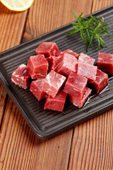 Diced Raw Australian Beef Cubes on Grill Plate with Rosemary Garnish