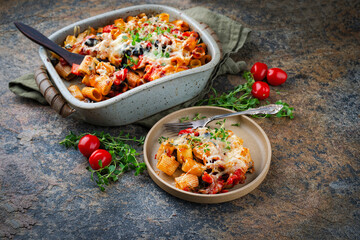 Homemade italian baked cheesy mezze maniche Pasta alla norma with eggplant, olives and tomatos in stoneware  casserole served as close-up