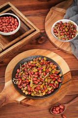 Spiced peanuts and dried fish snack with five-spice seasoning in wooden bowls on rustic table
