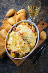 Artisan homemade oven baked tartiflette wih potato and reblochon cheese in casserole dish served as top view on a wooden board