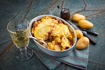 Artisan homemade oven baked tartiflette wih potato and reblochon cheese served as close-up in a casserole dish
