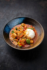 Traditional Thai red curry with king prawns and vegetable - kaeng phet as close-up in a bowl with jasmin rice