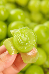 Fresh Green Qingti Fruit Carved into Rose Shape Held in Hand with Natural Fruit Background