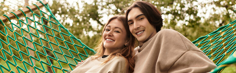 Fototapeta premium Young couple enjoying a cozy moment together in a hammock surrounded by nature