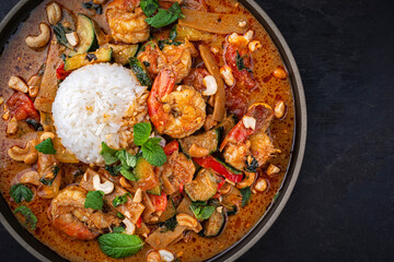 Traditional Thai red curry with king prawns and vegetable - kaeng phet served as top view in a bowl...