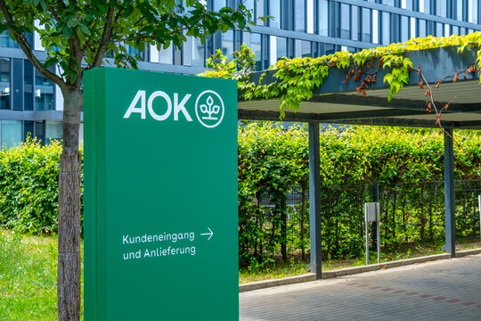 Green AOK logo German public healthcare and social security system, Gesundheitskasse Germany, modern corporate office building European health insurance, trust and stability,
