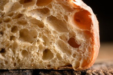 Porous bread crumb and crisp skin on rustic wooden board close up. Macro shot of artisan loaf texture