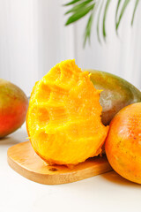 Fresh Ripe Mango Slices on Wooden Board with Tropical Palm Leaves Background