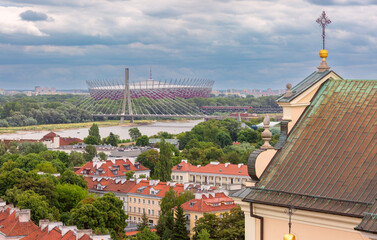 Panoramic view of the National Stadium and Vistula River in Warsaw, Poland, with residential rooftops in foreground